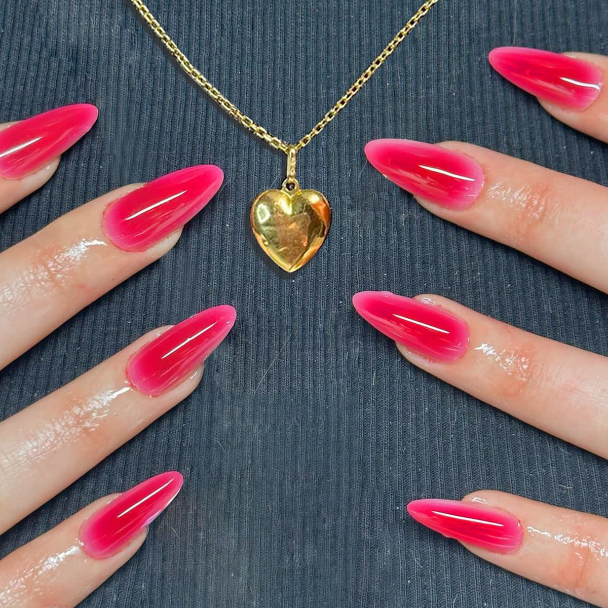 A set of long, vibrant pink press-on nails with a shiny finish, displayed on a person's hands against a neutral background.