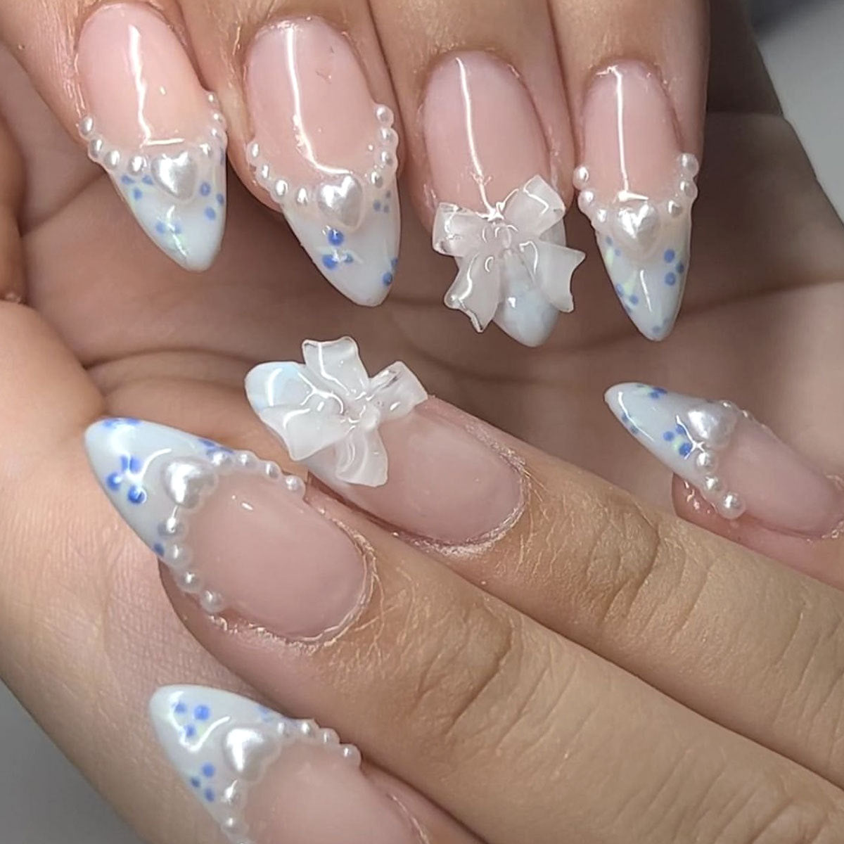 Close-up of a hand with decorative nail art featuring flowers and blue accents.