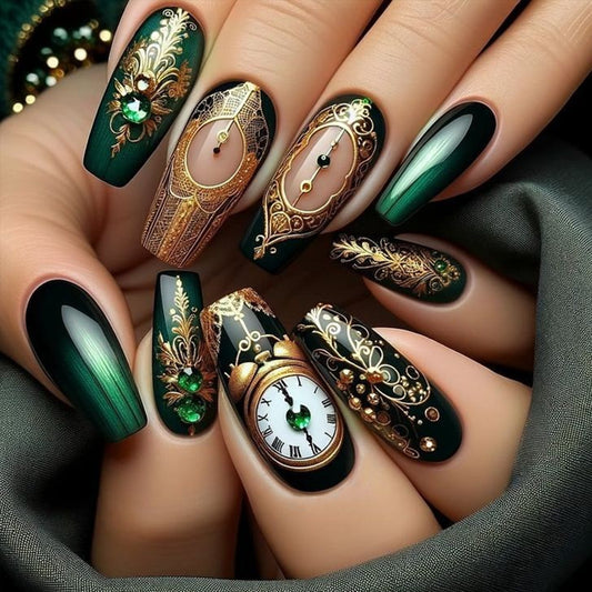 Nails with intricate designs, including clocks and green gemstones, on a dark fabric background.