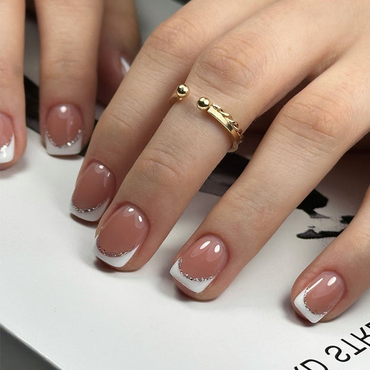 A set of press-on nails featuring a glittery French tip design in soft pink and white colors.