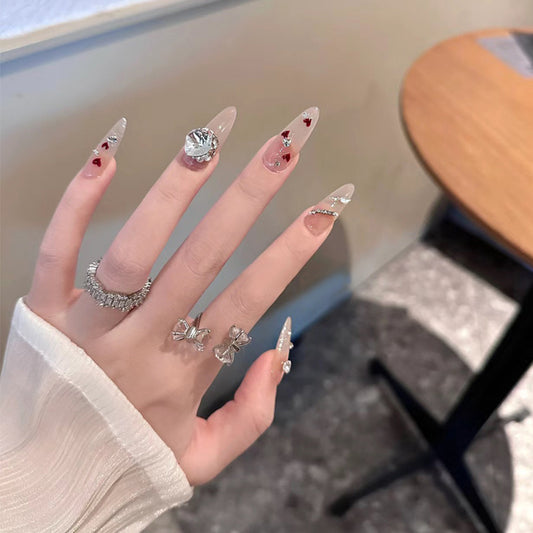 Hand with clear nail polish and decorative rings, blurred background