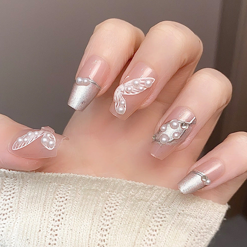 A set of long, gradated pink nails with white pearl and leaf accents designed for nail art.