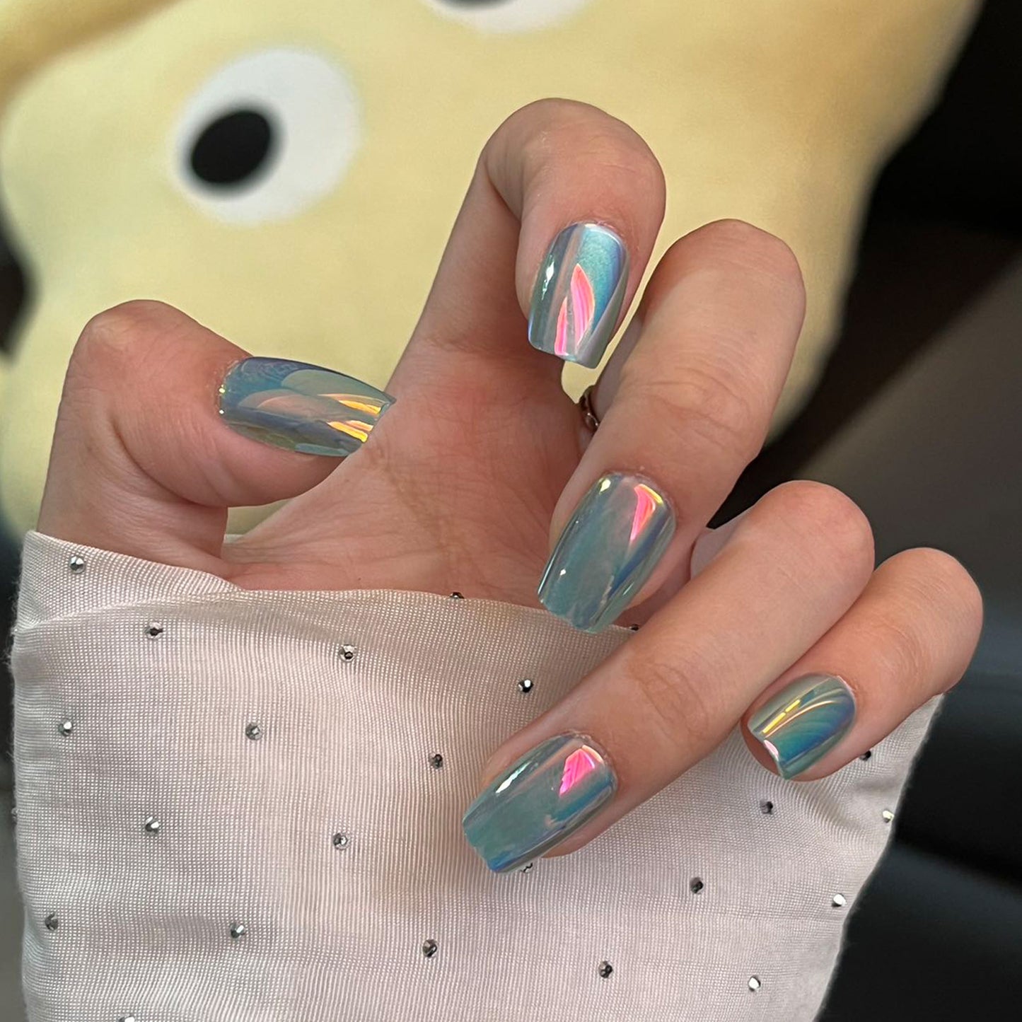 A set of press-on nails with a dreamy ocean vibe, featuring a medium square shape in aquamarine color with a stunning rainbow reflection.