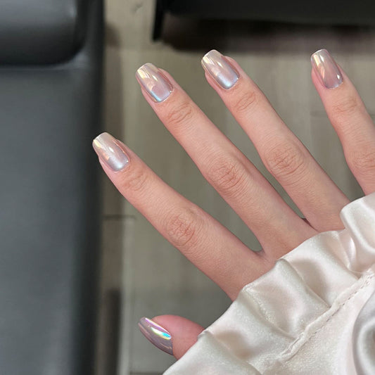 Close-up of a hand with iridescent nail polish against a neutral background
