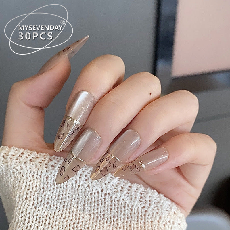 A set of beige almond-shaped press-on nails with leopard design embellishments.