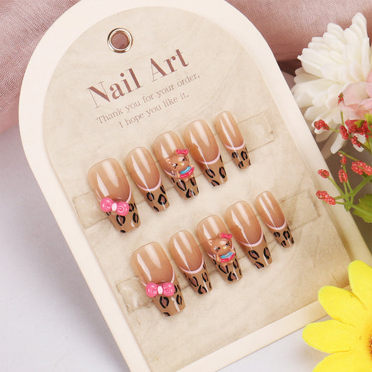 Set of nail art with leopard print and bow designs on a heart-shaped tray.