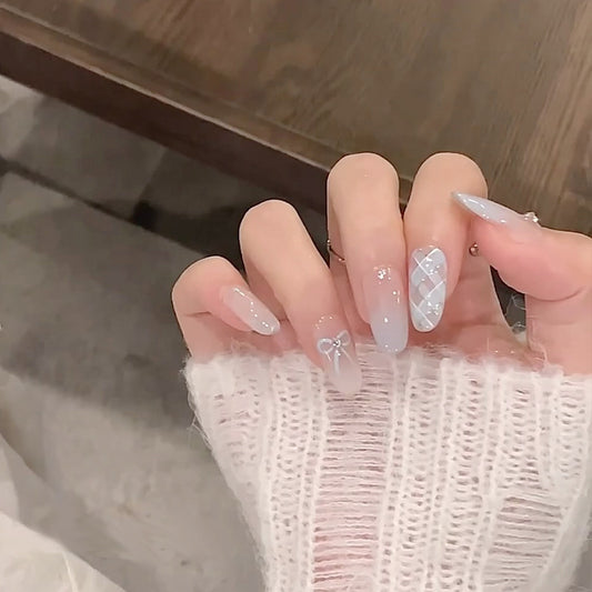 Close-up of a hand with decorative nails wearing a textured white sleeve.
