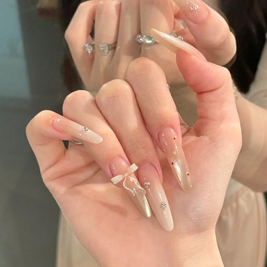 Elegant Charm Long Almond Shaped Beige Nails with Glitter and Bow Detail