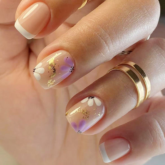Close-up of a hand with decorative nails and a gold ring.
