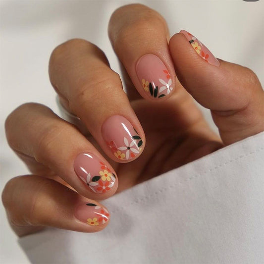 A set of press-on nails featuring a floral design with peach tones and a hand-painted pattern.