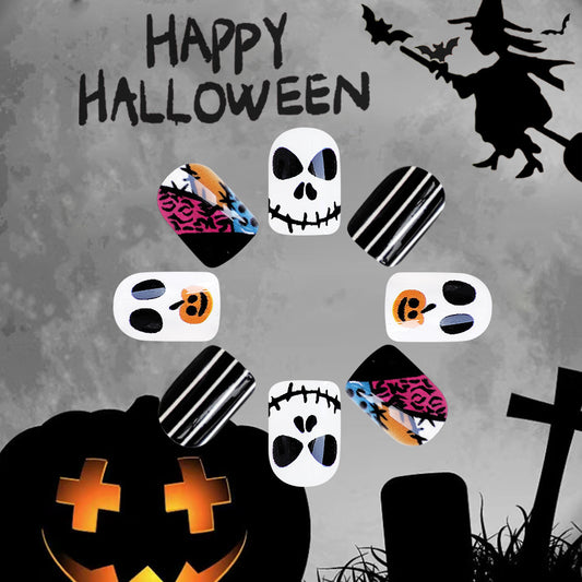 A set of multicolor press-on nails with skull and pumpkin designs, displayed against a Halloween-themed background with a witch and a pumpkin.