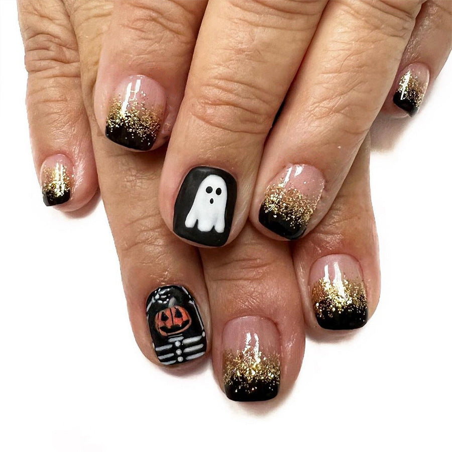 A set of press-on nails featuring a black and gold color scheme with decorative accents of a ghost and a pumpkin.