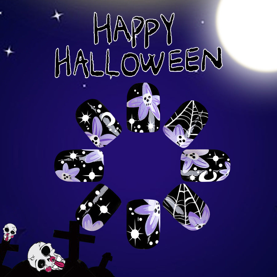 A set of black press-on nails with purple accents and glow-in-the-dark features, designed for Halloween. The nails are displayed against a dark background with a 'Happy Halloween' message and spooky decorations.