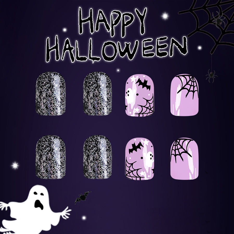 A set of press-on nails featuring various designs including black glitter, lilac, and pink nails with spider web and ghost motifs, and the text 'HAPPY HALLOWEEN' at the top.