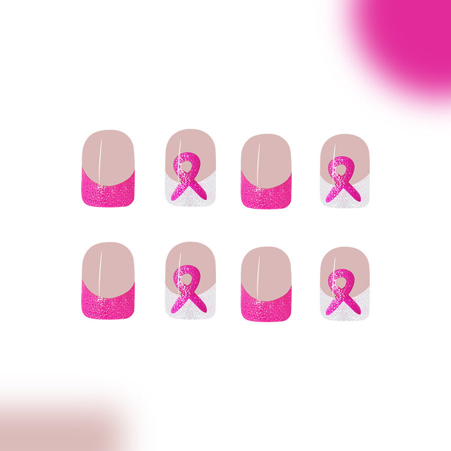 A set of pink press-on nails with glitter and a breast cancer awareness design, featuring a square shape and a subtle pink ribbon pattern.