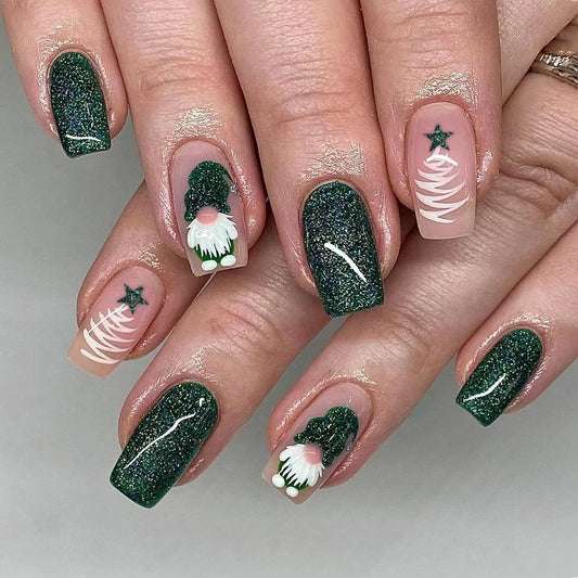 A set of long square green press-on nail extensions with festive Christmas designs, including stars and a Christmas tree.