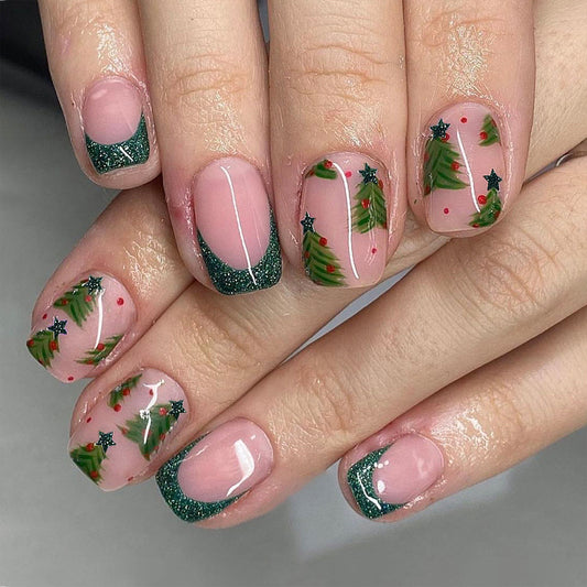 A set of press-on nails featuring a Christmas theme with green, pink, and glitter design, displayed on a hand.