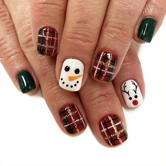 Nail art with Christmas-themed designs including a snowman, reindeer, and plaid patterns on a white background.