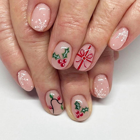 A set of short oval pink press-on nails decorated with Christmas ornaments and snowflake designs.