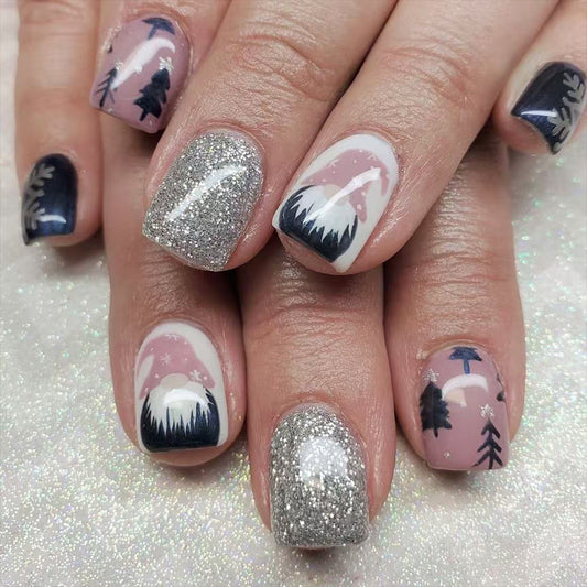 A set of press-on nails featuring a combination of pink, navy, and white colors with sparkling glitter finish and a scenic mountain design.
