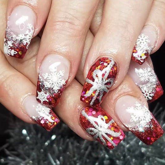 A set of press-on nails featuring a red and glittery design with snowflake patterns.