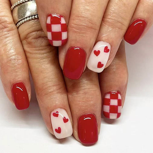 Nails with red and white checkered and heart designs on a neutral background
