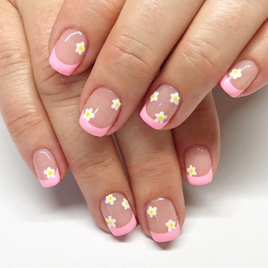 A photo of short square nails with pink French tips and daisy accents.
