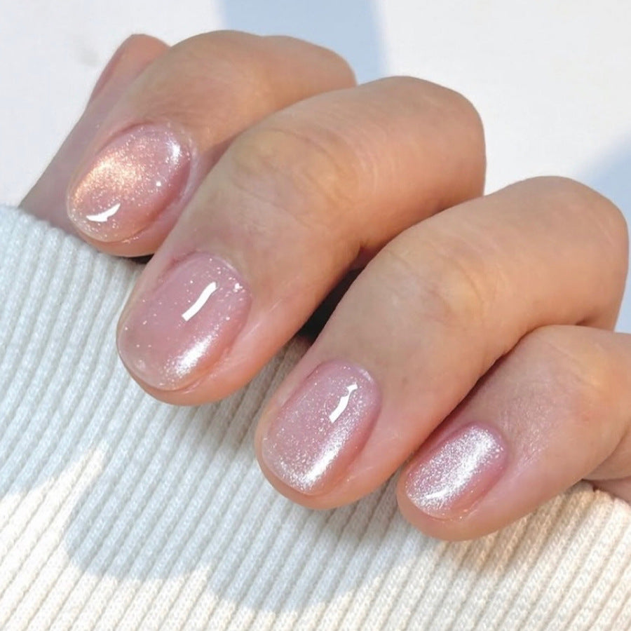 A close-up image of a hand with short squoval pink sparkling press on nails.