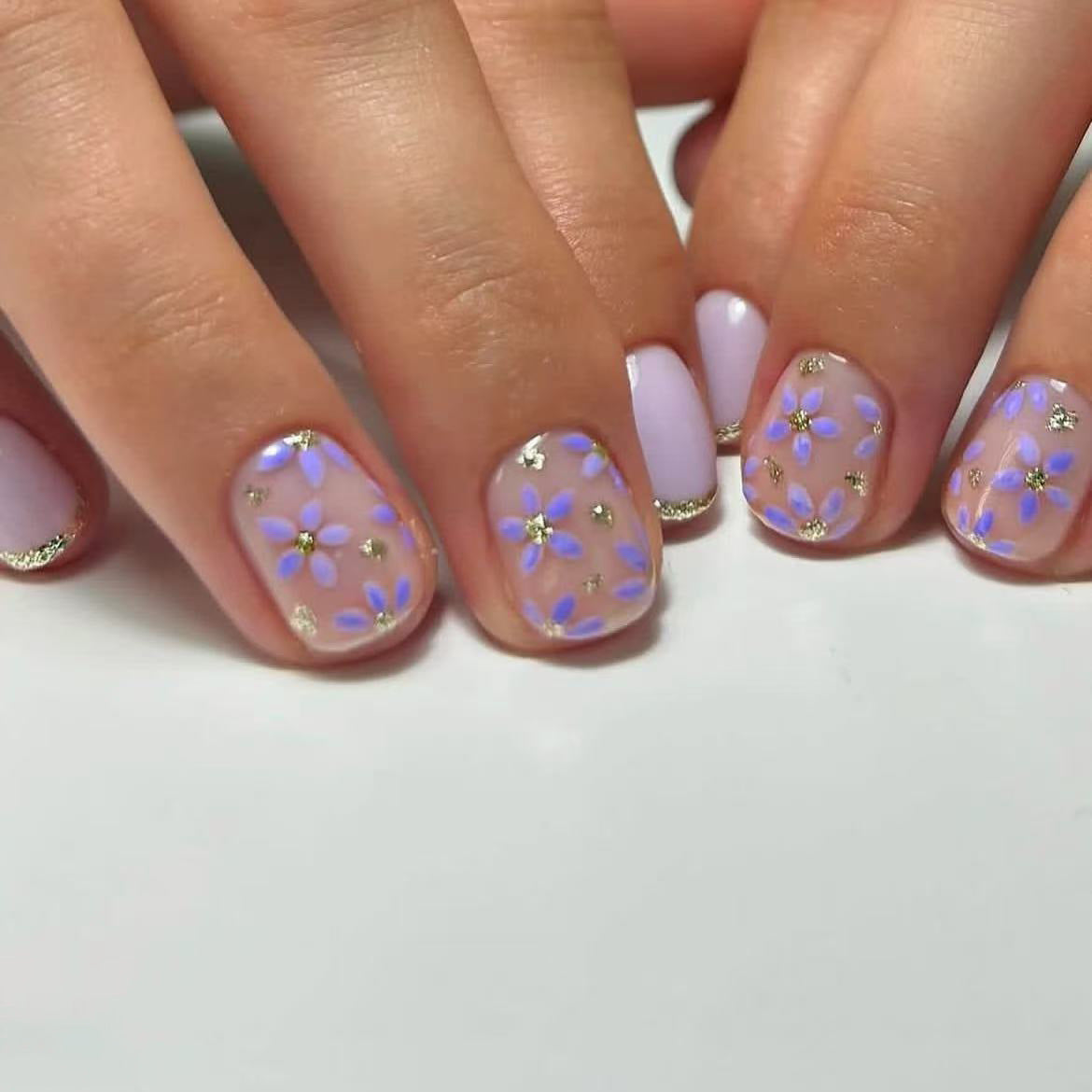 Close-up of hands with floral nail design on a white background