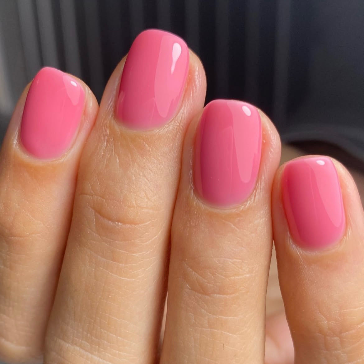 Close-up of a hand with pink nail polish on a blurred background