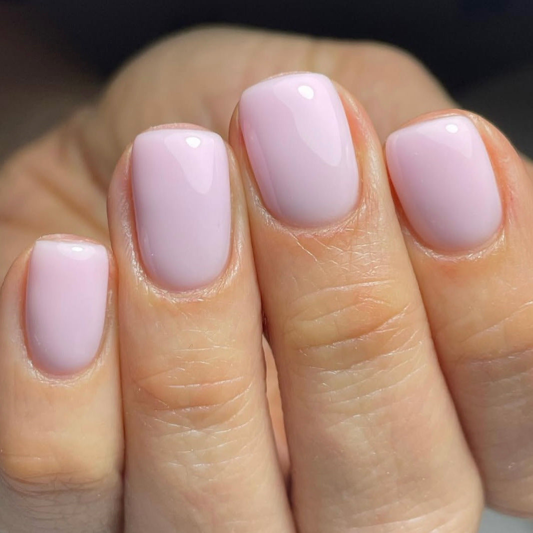 Close-up of a hand with light pink nail polish on a blurred background