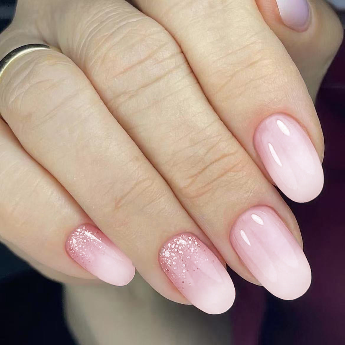 Close-up of hands with pink and glittery nail polish on a blurred background