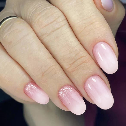 Close-up of hands with pink and glittery nail polish on a blurred background