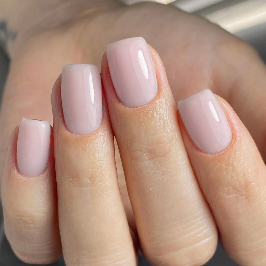 Close-up of a hand with light pink nail polish on a neutral background