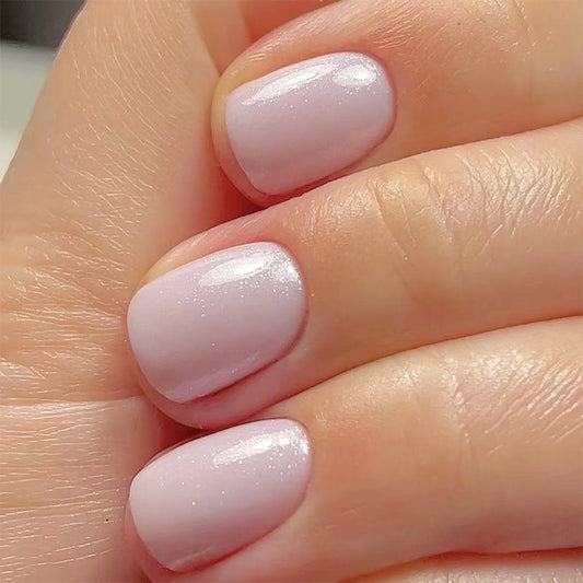 Close-up of a hand with light pink nail polish on a neutral background