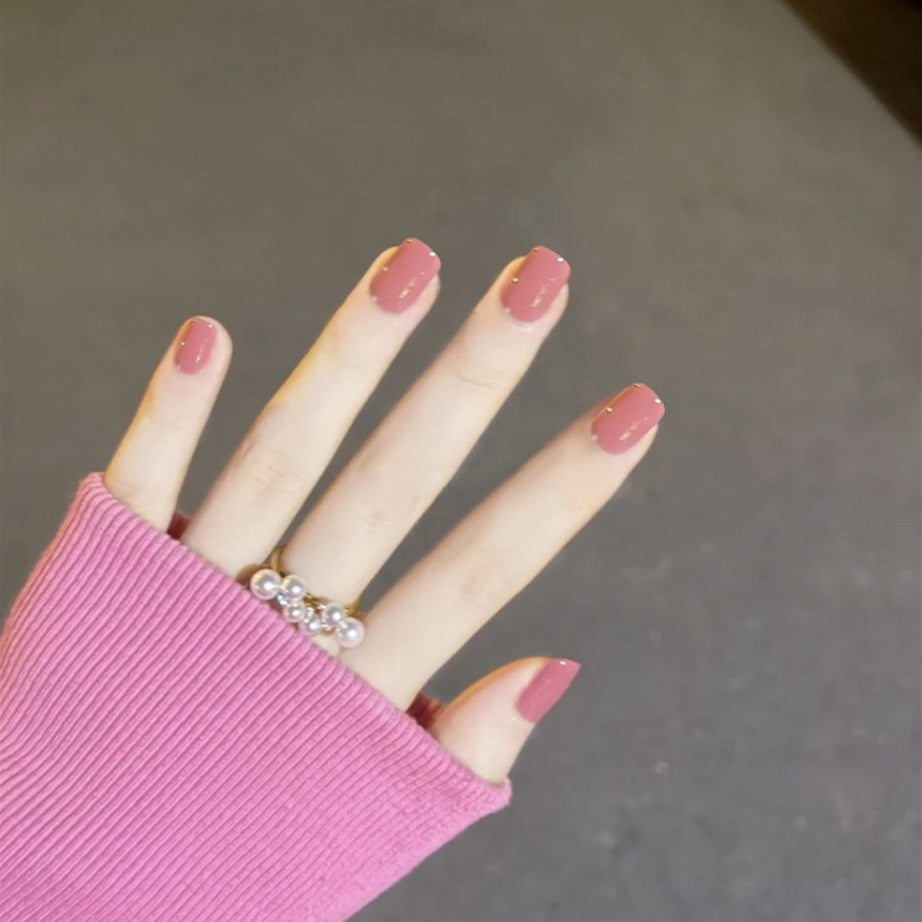 Hand with pink nail polish and a pink sleeve on a neutral background