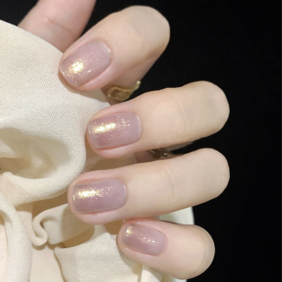 A pair of short-length square-shaped press-on nails with a glossy, multicolored finish and sparkling accents, displayed on a hand.