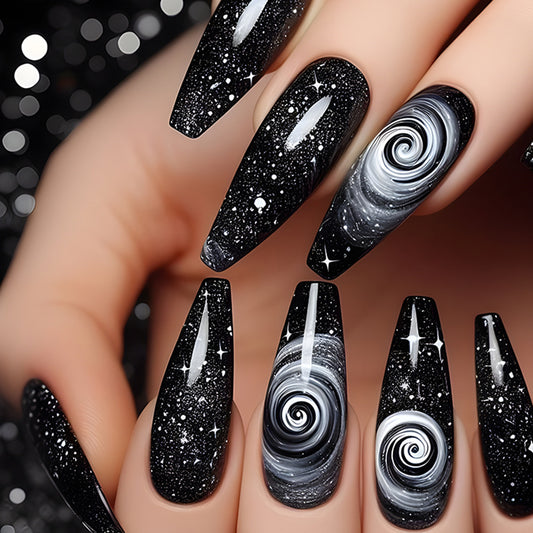 A set of long black nails with a swirling cosmic design and glitter.