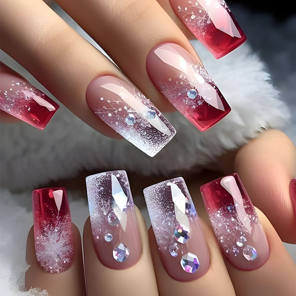 A set of press-on nails featuring a medium square shape with a gradient from clear to red color and sparkling rhinestones scattered throughout.