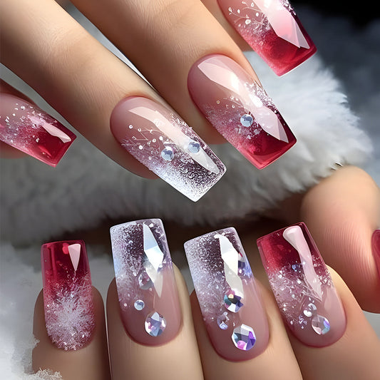 A set of press-on nails featuring a medium square shape with a gradient from clear to red color and sparkling rhinestones scattered throughout.