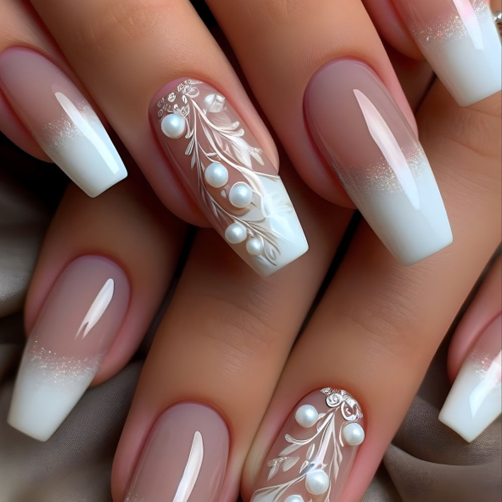 Nails with white and beige gradient design featuring pearls and floral patterns.