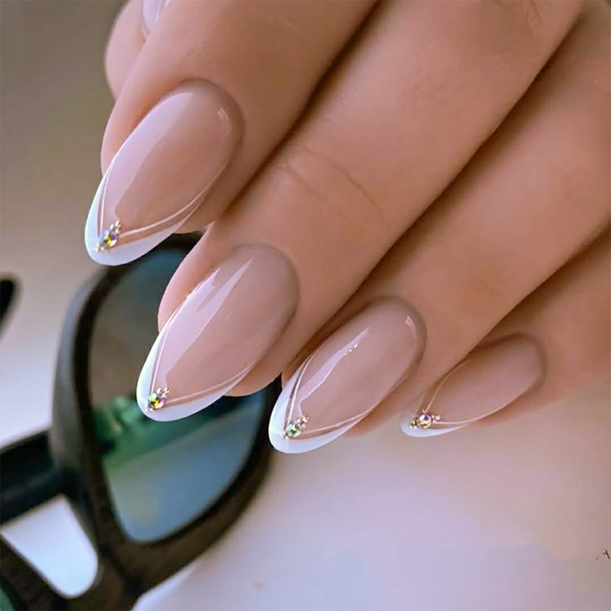 Close-up of a hand with beige nail polish and small decorative elements.