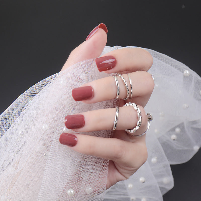 Hand with red nail polish wearing silver rings against a dark background