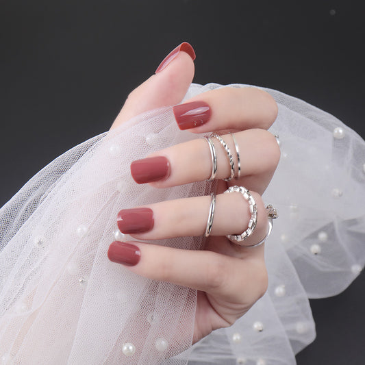 Hand with red nail polish wearing silver rings against a dark background