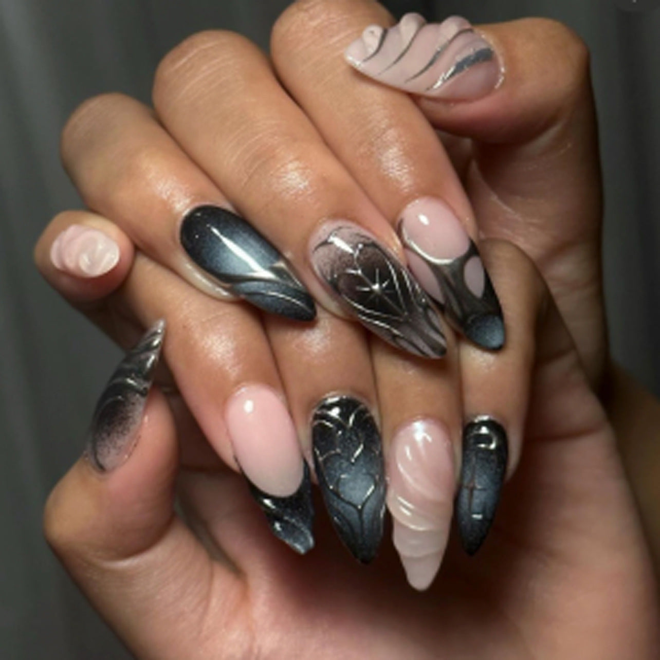 Hand with black and silver feather nail art on a neutral background