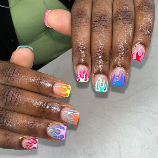 Close-up of hands with colorful flame nail art on a neutral background