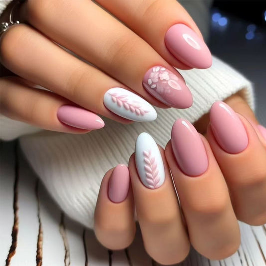 Close-up of hands with pink and white nail polish featuring leaf designs.