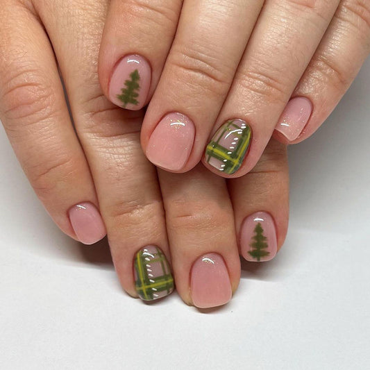 Close-up of hands with plaid and tree nail art on a white background