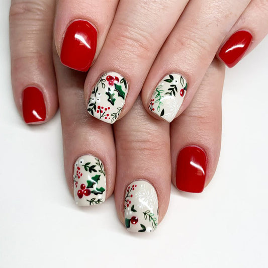 A set of press-on nails featuring a holiday design with red, cream, and green colors, and a floral pattern of holly and berries.