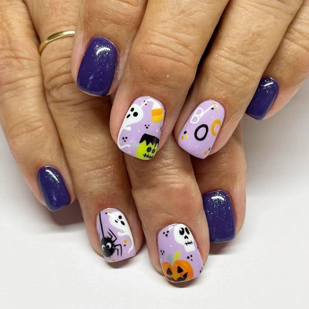 A set of press-on nails featuring a Halloween theme with designs including a ghost, pumpkin, and various colors like purple and orange.